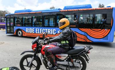 A motor bike rider in Nairobi, October 19, 2022, next to an electric bus