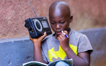 Igihozo, 11, listens to a lesson on a radio after his school was closed in Rwanda.