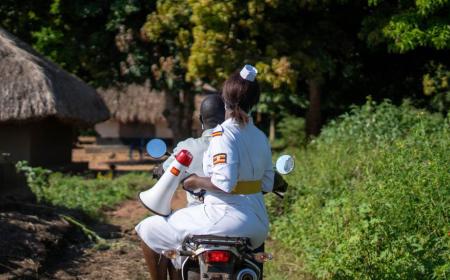 Un agent de santé ougandais, utilise un mégaphone pour encourager sa communauté à se faire vacciner.