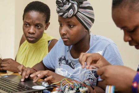 Young women in AkiraChix hardware and electronics class build circuit boards.