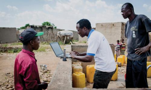 An official checks data from an internet-based water monitoring device at a borehole in Basbedo, Burkina Faso. Photo: Panos/Andrew McConnell