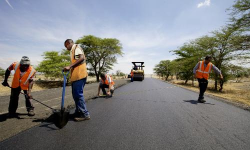 Workers take measurements while laying the tarmac on a new road being built near Arusha, Tanzania. Africa needs funds for such development projects. Panos/Frederic Courbet