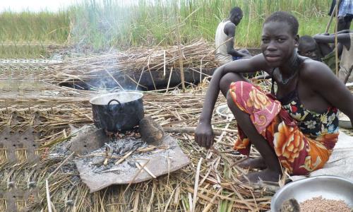 An internally displaced woman seeking refuge from the ongoing violence in the swamps of Unity state, cooks her last supply of sorghum. Photo: FAO South Sudan