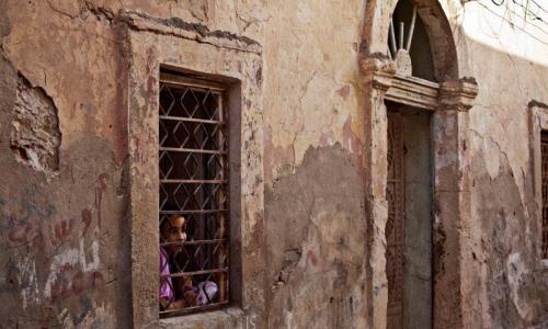 A girl looks out of her house window in Benghazi, Libya. Photo: UNSMIL