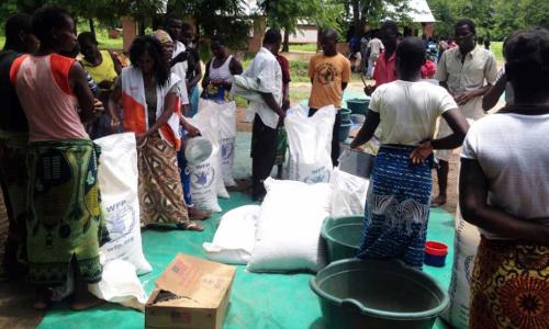 People gather at Mikolongo school in Chikwawa district, Malawi, to receive rations of maize, pulses, oil and fortified corn soya blend from WFP to prevent malnutrition.