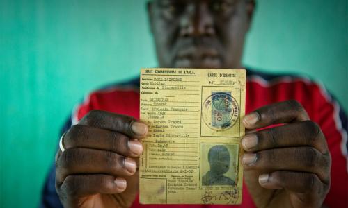 Un homme répondant au nom de Oumar, qui risquait de devenir apatride, brandit la carte d’identité de son père, datant de l’époque coloniale française. Photo : HCR/Hélène Caux