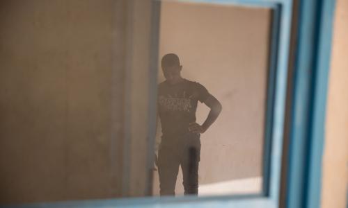 Un jeune homme attend dans un centre de transit de l’OIM à Agadez, au Niger. Photo OIM 2016/Amanda Nero