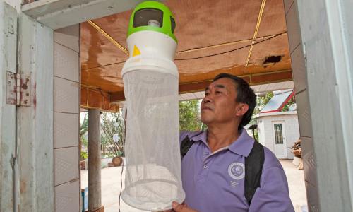 Health worker checking the installation of an anti-mosquito device at the entrance of a house. Such devices may help to trap mosquitoes, flies and insects. Photo: WHO/TDR/S. Lim
