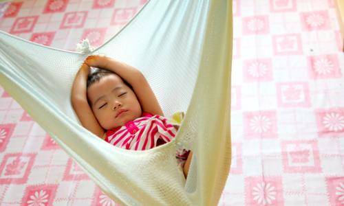 Un bébé du groupe ethnique autochtone des Kadazandusun dort dans un berceau traditionnel en tissu dans un centre d’apprentissage et de garde d’enfants dans le district de Penampang, en Malaisie. Photo : UNICEF / Giacomo Pirozzi