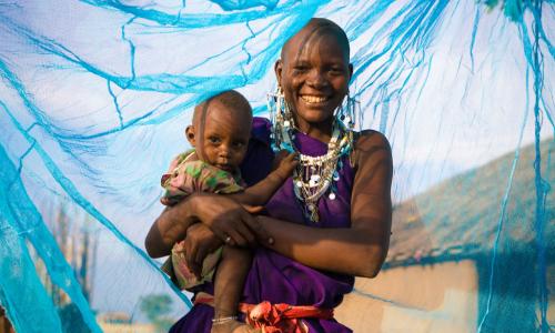 Une mère souriante avec son jeune garçon sous un filet insecticide, à Arusha, en Tanzanie. 