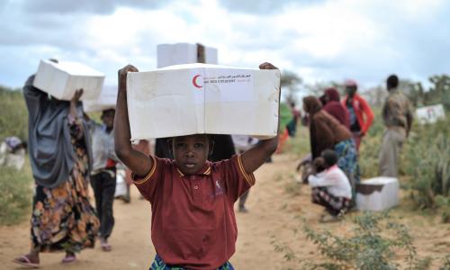 A young boy carries away a box of food from a distribution centre in Afgoye, Somalia. Photo: AU/UN/IST/Tobin Jones