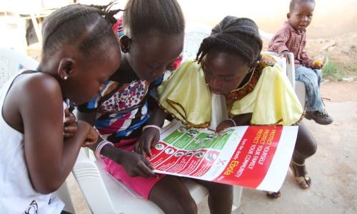 Girls in the city of Voinjama look at a poster that displays information and illustrations about how to prevent the spread of Ebola. Photo: UNICEF/2014/Liberia/Jallanzo