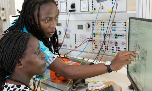 Two students practicing with wind, solar and other models on computer.