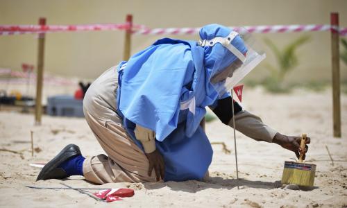 A member of an Explosive Ordnance Disposal team brushes sand off a mortar shell during a demonstration held by the United Nations Mine Action Service (UNMAS) in Mogadishu, Somalia.