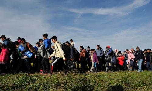 A column of refugees and migrants is walked across fields by police in Slovenia in this October 2015 file photo.  © UNHCR/Mark Henley