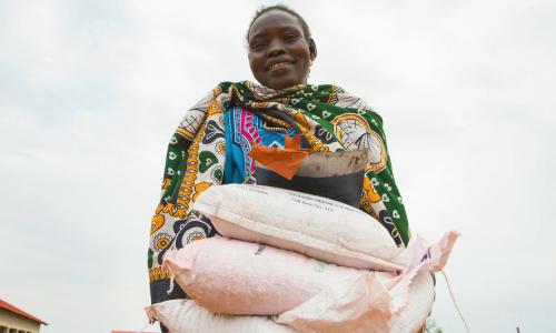 A woman carries sacks of seeds distributed to families in South Sudan during the COVID-19 pandemic.
