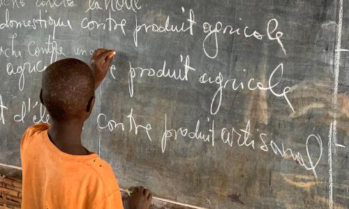 A young Burundian refugee completes an exercise on a blackboard in Nyarugusu Refugee Camp, Tanzania.