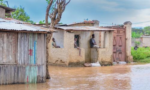 Children sit idly with their father, observing the destruction of their community’s homes in Bujumbura Rural Province, Burundi.