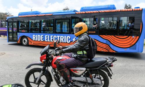 A motor bike rider in Nairobi, October 19, 2022, next to an electric bus