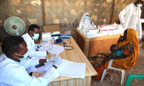 Wahudumu wa afya katika kiliniki inayosaidiwa na UN karibu na kambi ya wakimbizi wa ndani ya Ceel Jaale katika eneo la Belet Weyne wakimuhudumia mama na bintiye mdogo.