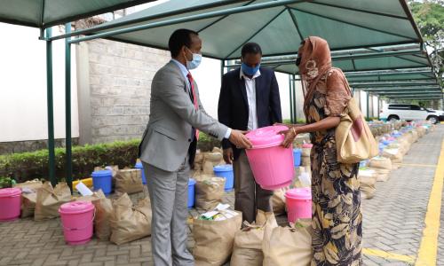 Meles Alem, Ethiopian Ambassador to Kenya handing over food donation to one of the beneficiaries.
