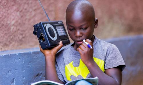 Igihozo, 11, listens to a lesson on a radio after his school was closed in Rwanda.