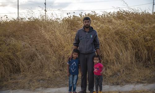 Baba mzazi kutoka Syria anasimama na watoto wake katika kambi ya Bardarash mjini Duhok, Iraq, siku moja baada ya kuwasili.