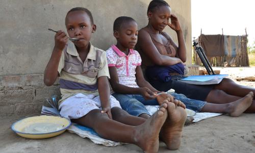 Mama akiwafundisha wanae katika wilaya ya Shamva nchini Zimbabwe wakati wamlipuko wa COVID-19.