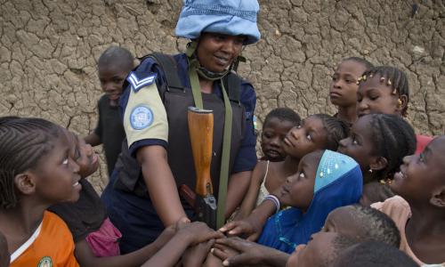 A Rwandan peacekeeper from the UN Multidimensional Integrated Stabilization Mission in Mali (MINUSMA) Formed Police Unit (FPU) speaks with children while patrolling the streets of Gao in northern Mali. Photo Credits: UN Photo/Marco Dormino