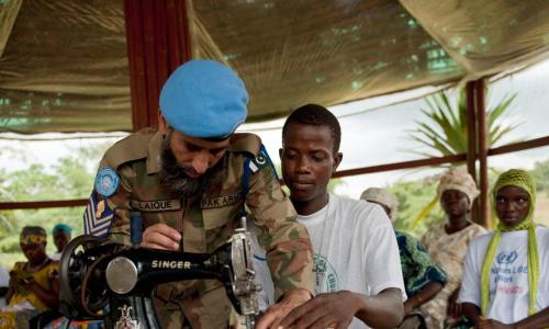 Mlinda amani kutoka Pakistani akimsamdia mwananchi kujifunza kushona nguo.  Picha: UN /Staton Winter