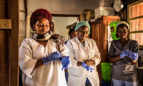 Health workers in the DRC put on gloves on before checking patients at the hospital.