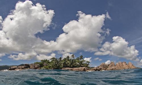 Island with water in foreground and blue sky above.
