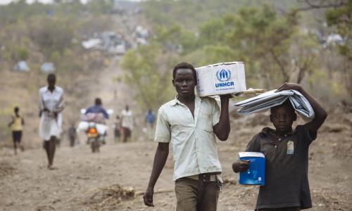 Des réfugiés sud-soudanais avec des articles de secours dans le site pour réfugiés de Bidibidi, en Ouganda. Photo HCR/David Azia