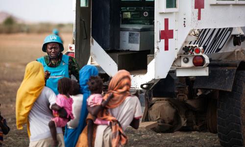 Un Casque bleu de la MINUAD avec des enfants dans le village de Karbab, au Sud-Darfour, lors d’une patrouille de routine. Photo ONU/Albert Gonzalez Farran