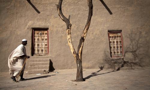 Mwananchi akipita pembezoni ya Msikiti wa Djingareyber, Timbuktu, Mali. Mji huu hivi ni moja ya urithi wa dunia ulioko hatarini. 