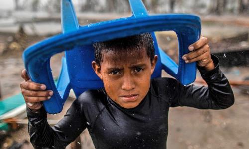 Young boy tries to shield himself from storm in Central America.