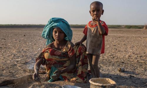 A young girl cooks in a rural village in Ethiopia, where the land has been affected by recurrent droughts.