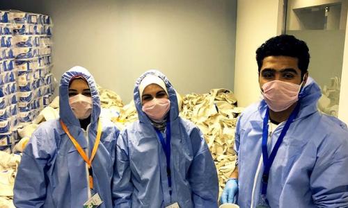 Y-Peer volunteers wear protective gear as they assemble the dignity and hygiene kits.