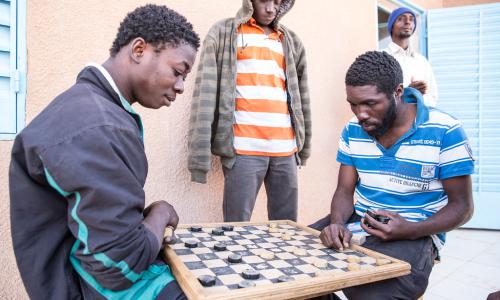 Migrants play a board game at IOM Transit Center in Agadez, Niger (2016).
