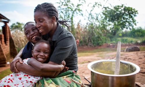 Happy children as their mother prepares porridge.