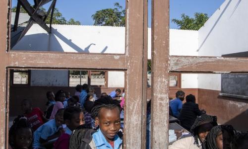 A boy looks through a classroom window.